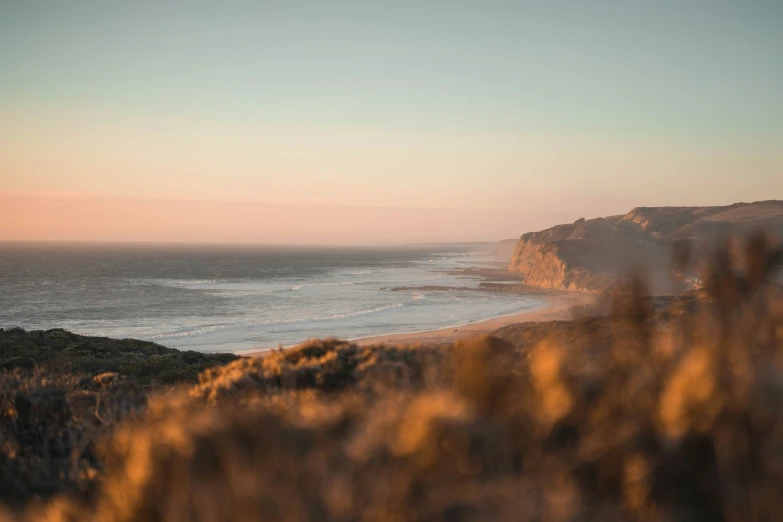 an ocean view from the hills to a sandy beach