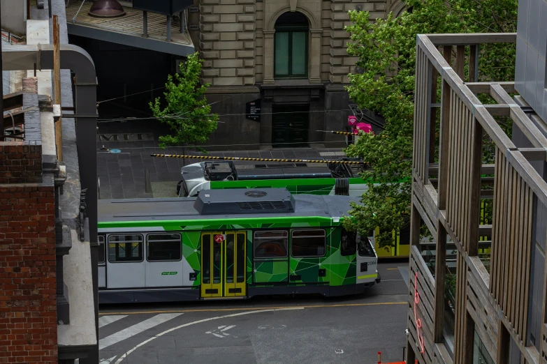 a green bus going down a street near a building