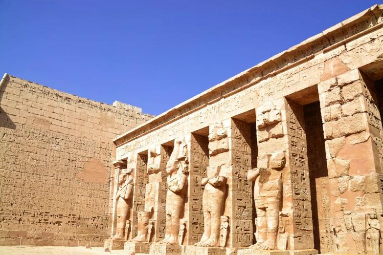 ancient statues line the outside of a large building