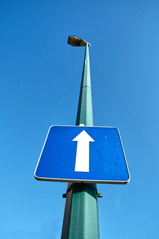 a close up of a blue street sign with an arrow pointing upward