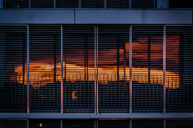 orange clouds behind metal bars on a large building