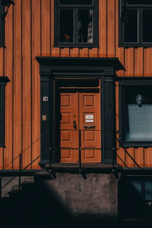 a wooden building with two windows and an orange wall