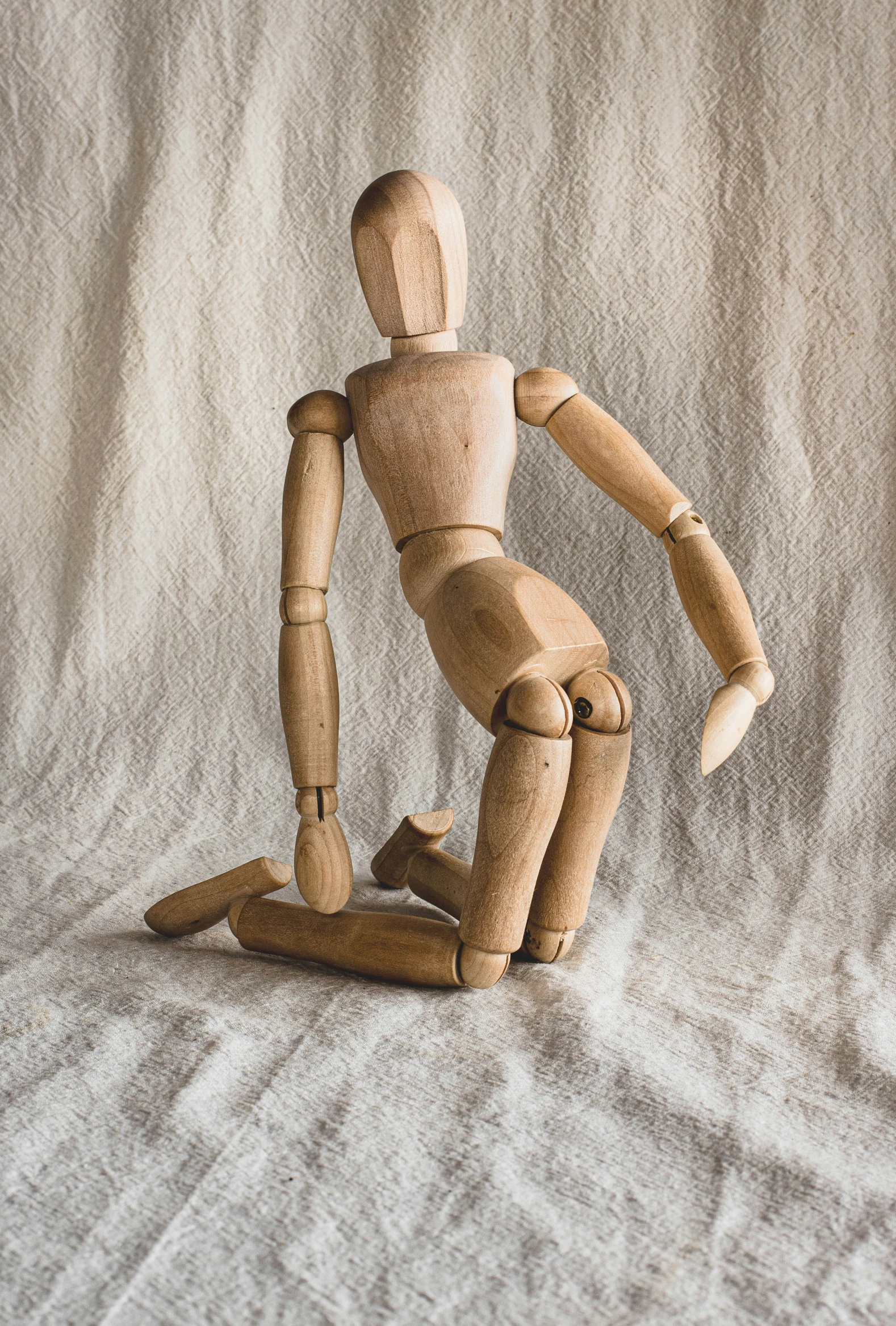 the wooden articulated doll is posed for pos