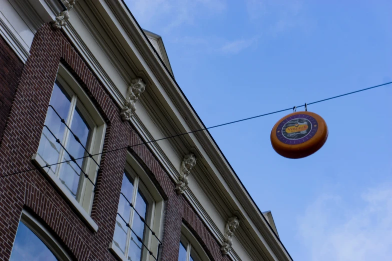 an orange round sign on a wire next to a building