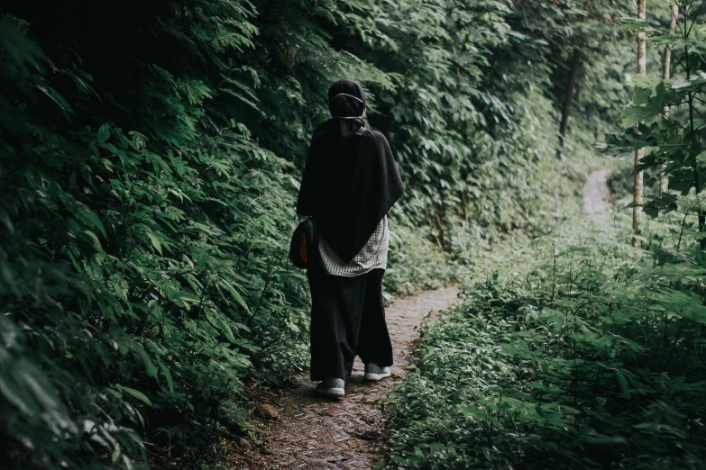 a man is walking down a path through the trees