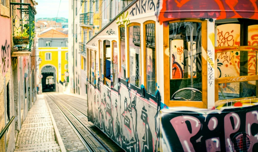an electric train traveling through a city with graffiti all over the side