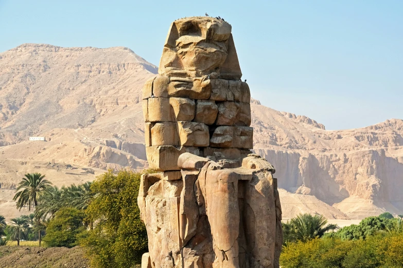 a tall stone column sitting next to mountains