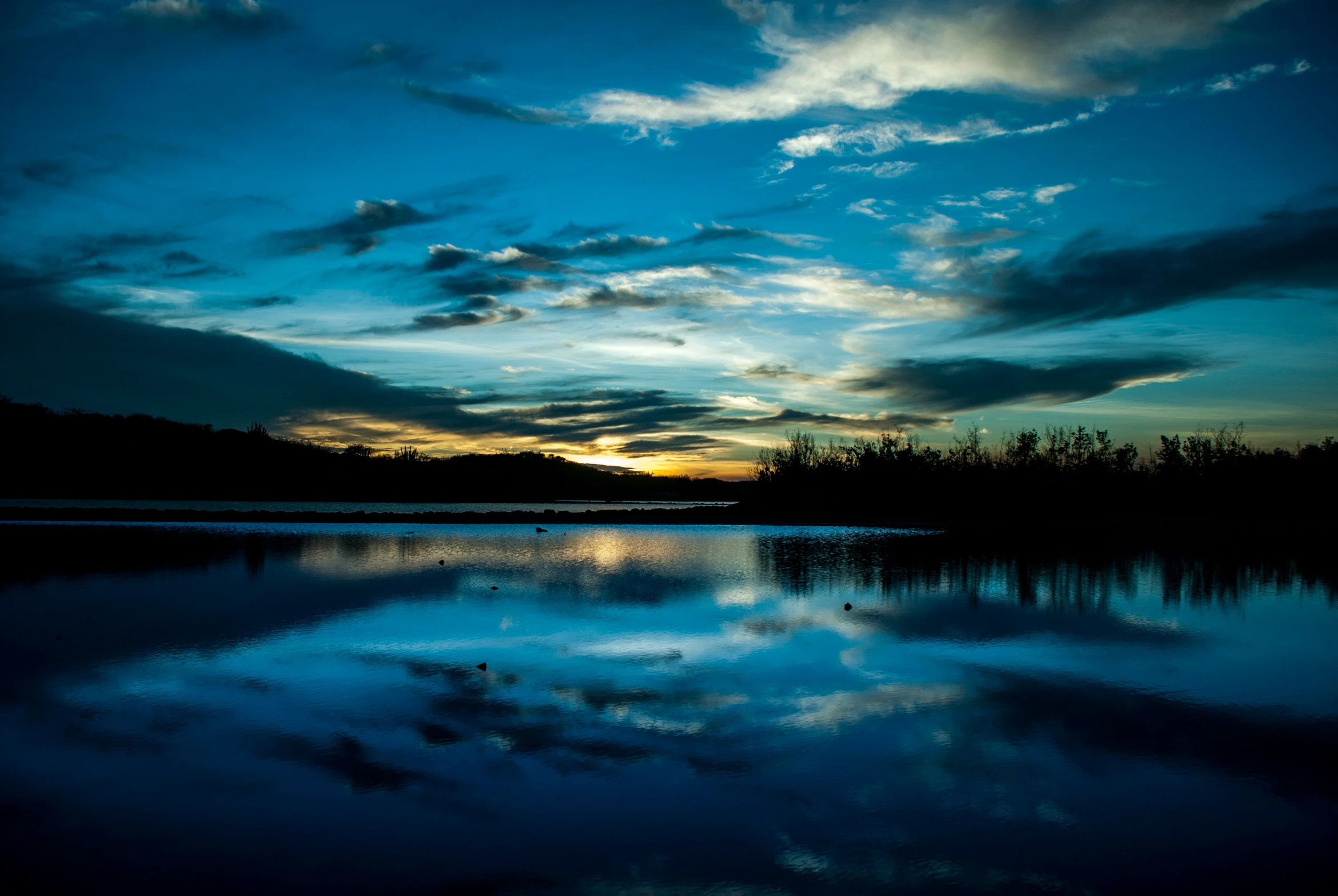 the clouds reflect on the water at sunset