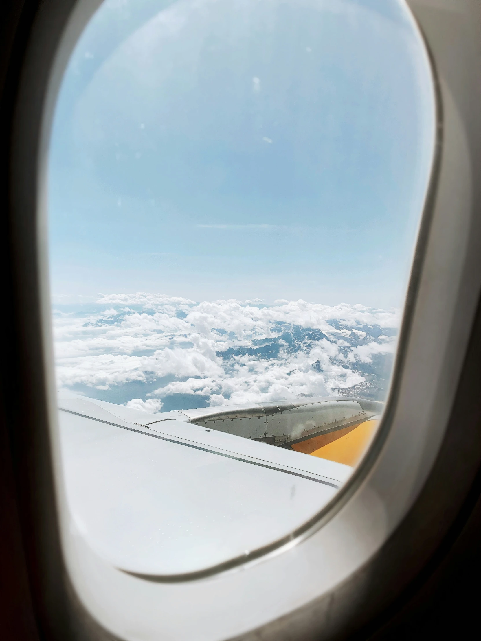 an airplane window with clouds and sky in the background