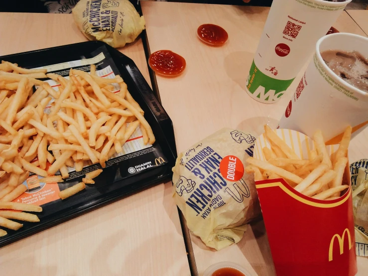 a tray filled with french fries next to a container of ketchup and a drink