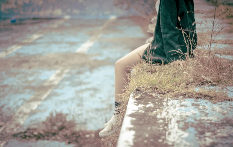 a woman wearing boots sitting on a ledge