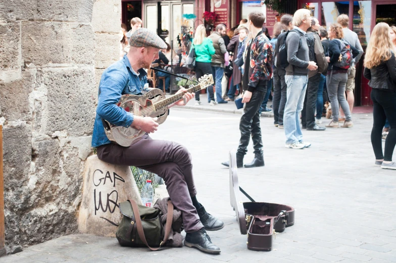 a man sitting on a bench while playing a guitar