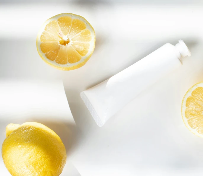 a peeled lemon is next to two tubes and slices