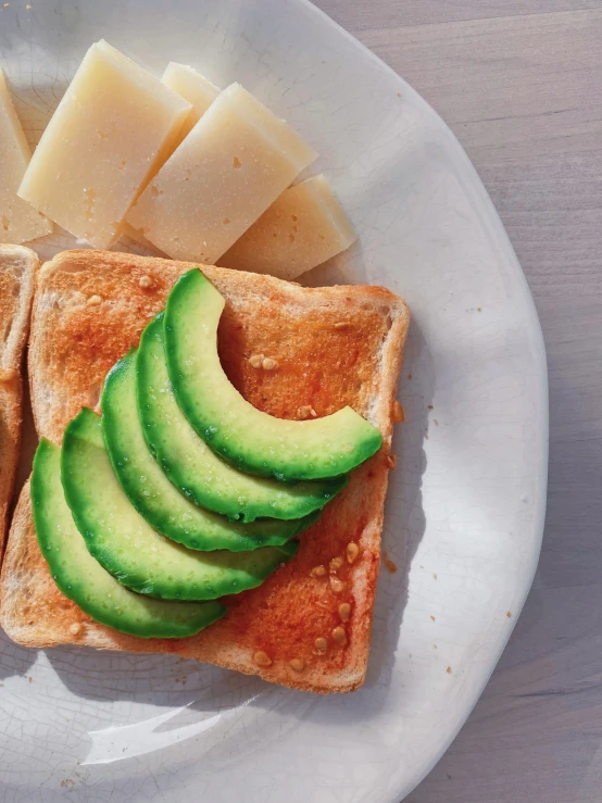 the plate has an avocado on it next to a piece of bread