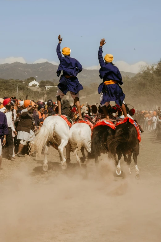 a group of men on horses are riding in a dusty field