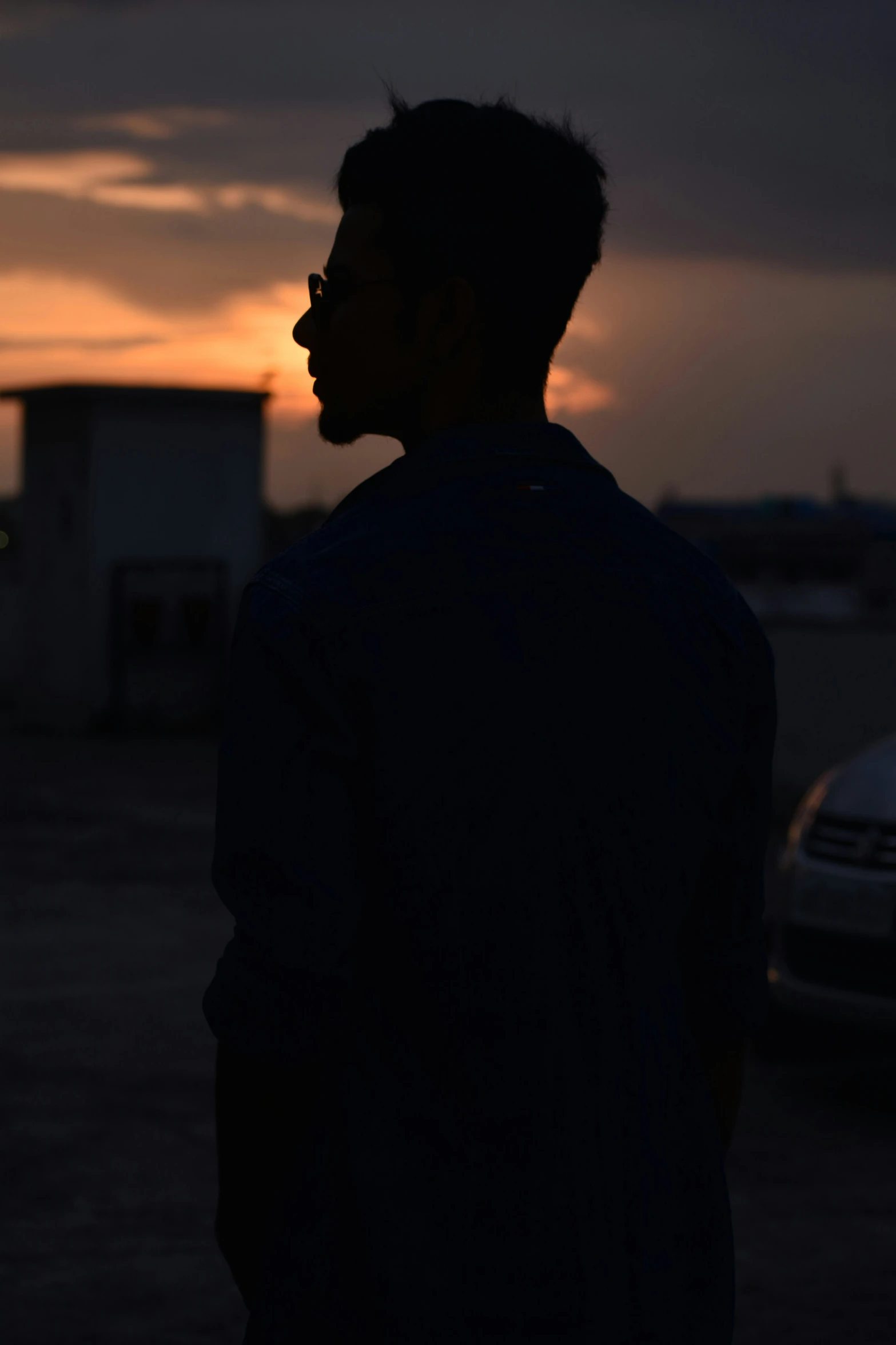 a man is standing in the parking lot while the sun sets