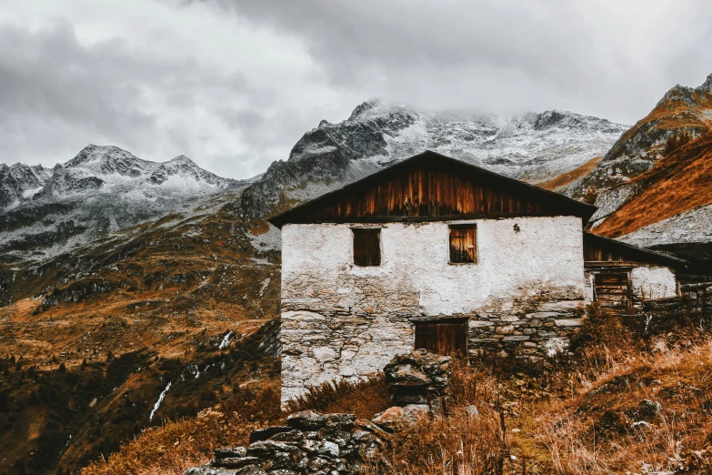 a house that is made from white bricks and surrounded by a mountain range