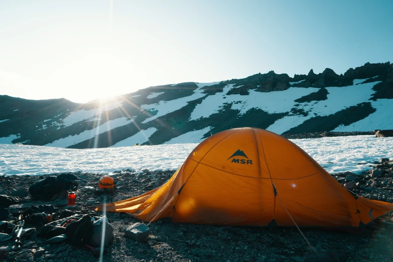 the orange tent is sitting in the sand