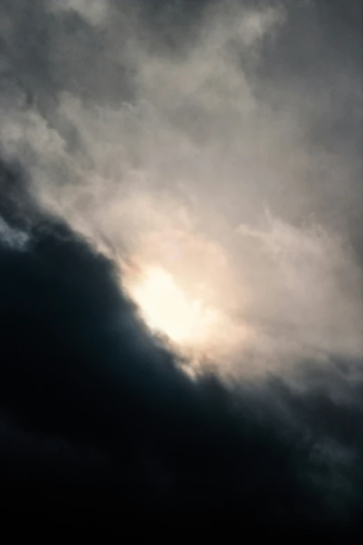 the sun shining through dark clouds above a airplane