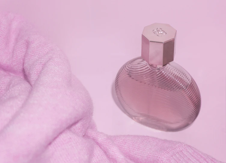 a bottle of perfume sitting on top of pink material