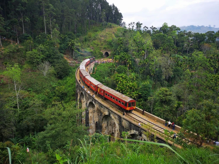 a train traveling over a bridge surrounded by lush green hills