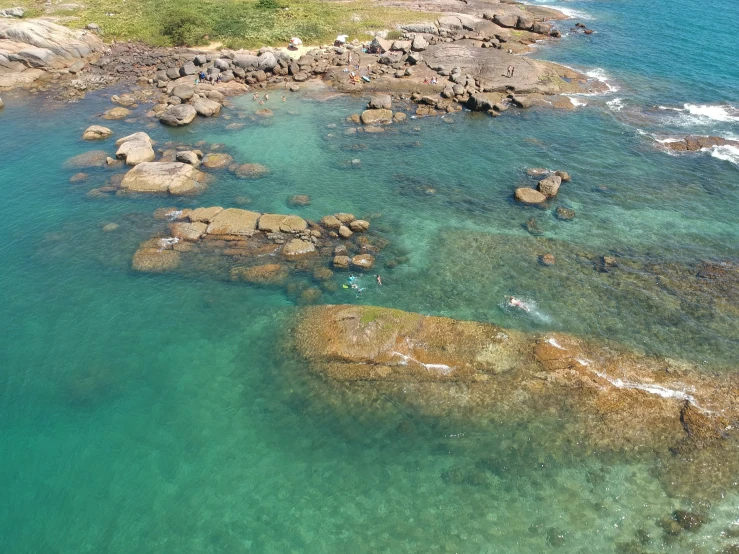 an aerial view of several rocks, some clear blue water