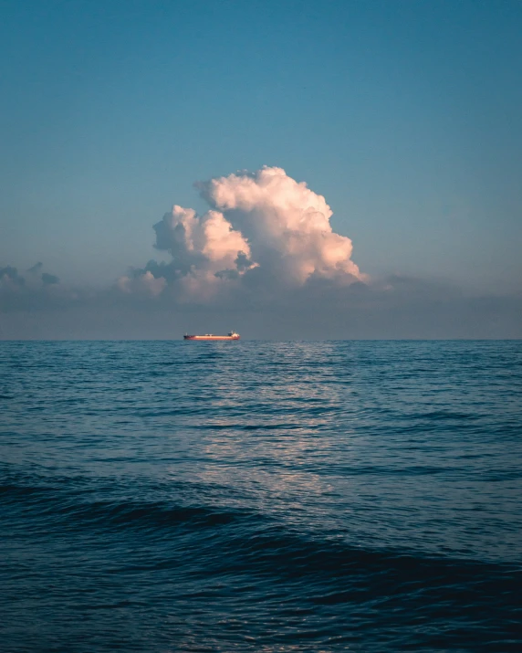 a large white cloud is flying over the ocean