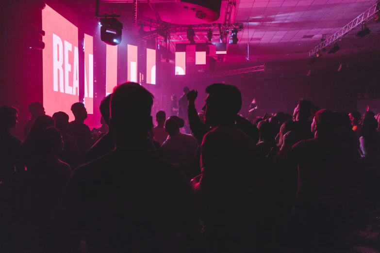 a group of people in a club or nightclub in front of the neon lit screen