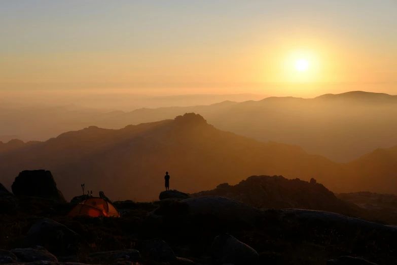 a sunrise over a mountain and the person standing in front