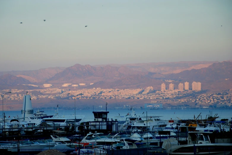 a group of boats docked in a harbor next to mountains