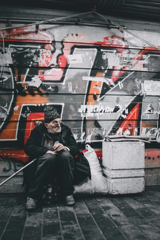 a man sitting in front of a wall covered in graffiti