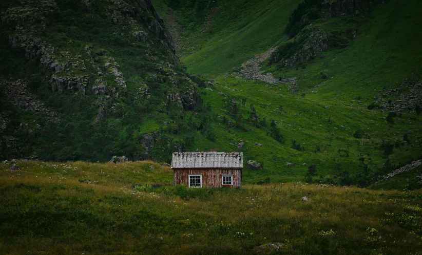 a building with a roof sits on a grassy hill