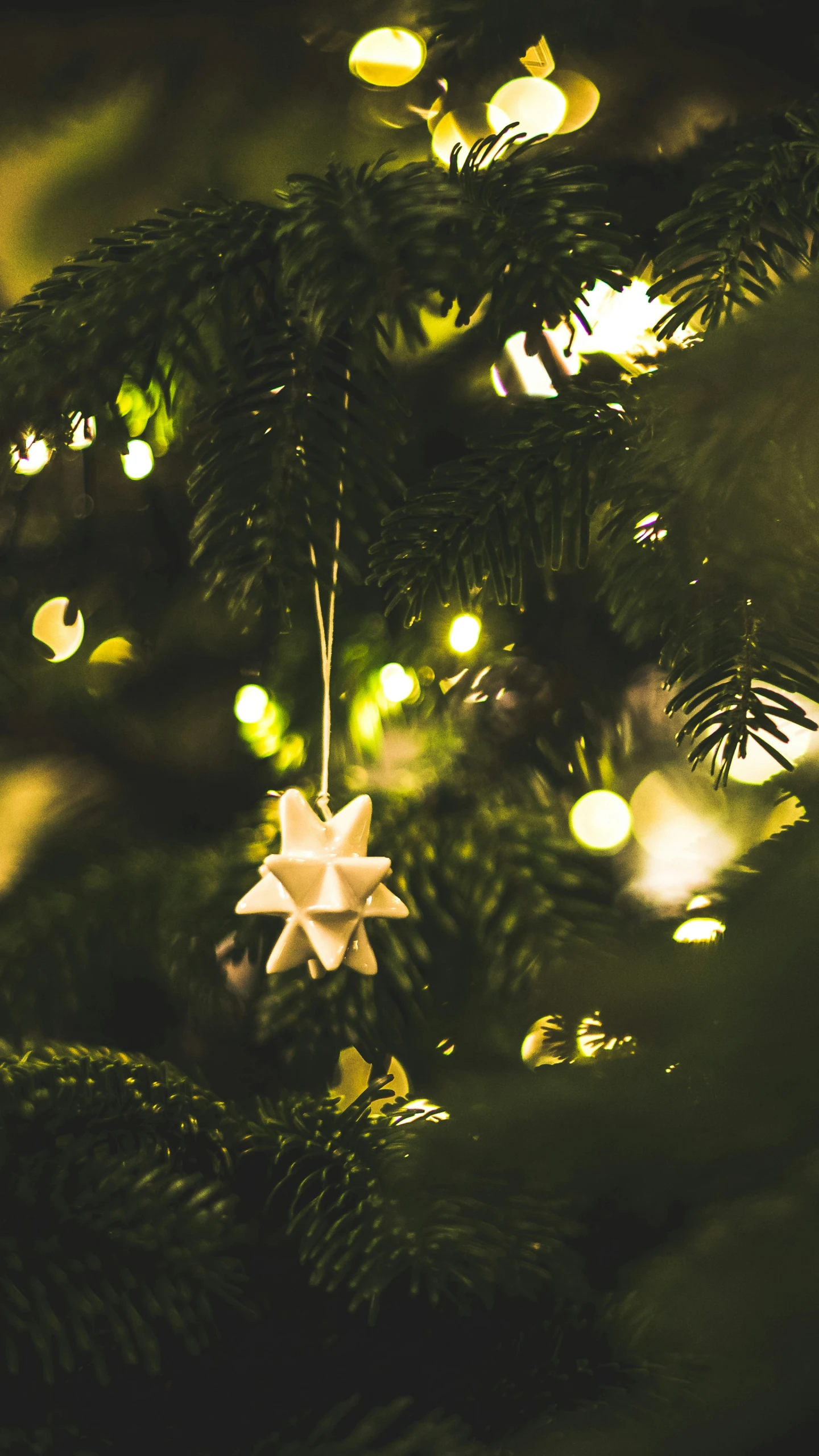 a white origami ornament sits on top of a christmas tree