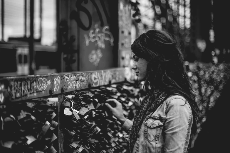 a woman is standing next to a fence looking away