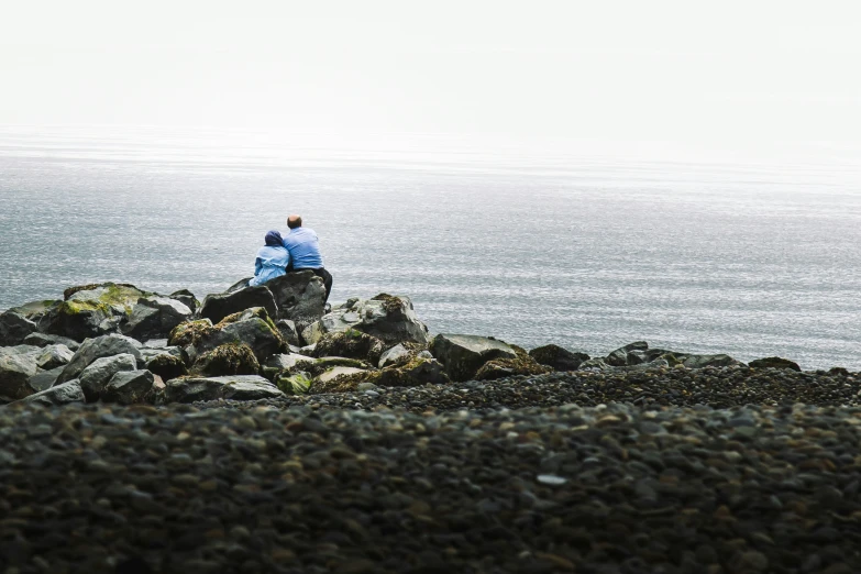 a person sitting on top of a rock by the ocean