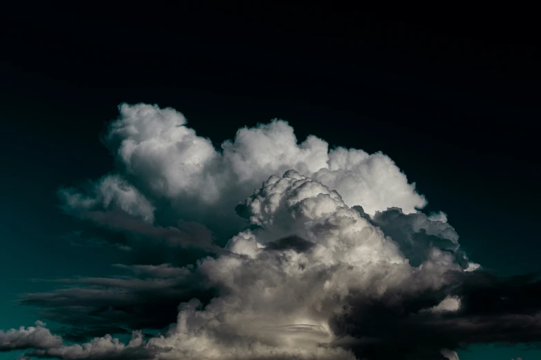 a large cloud filled sky above the ground