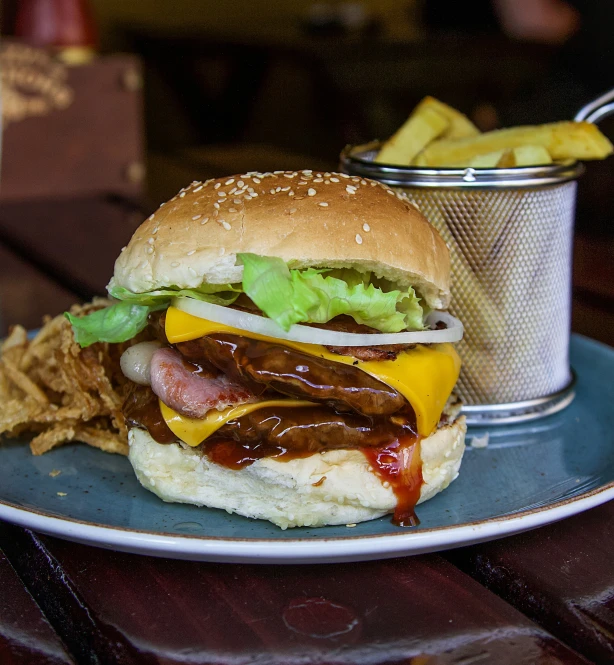 a hamburger with onion, lettuce and cheese next to some chips