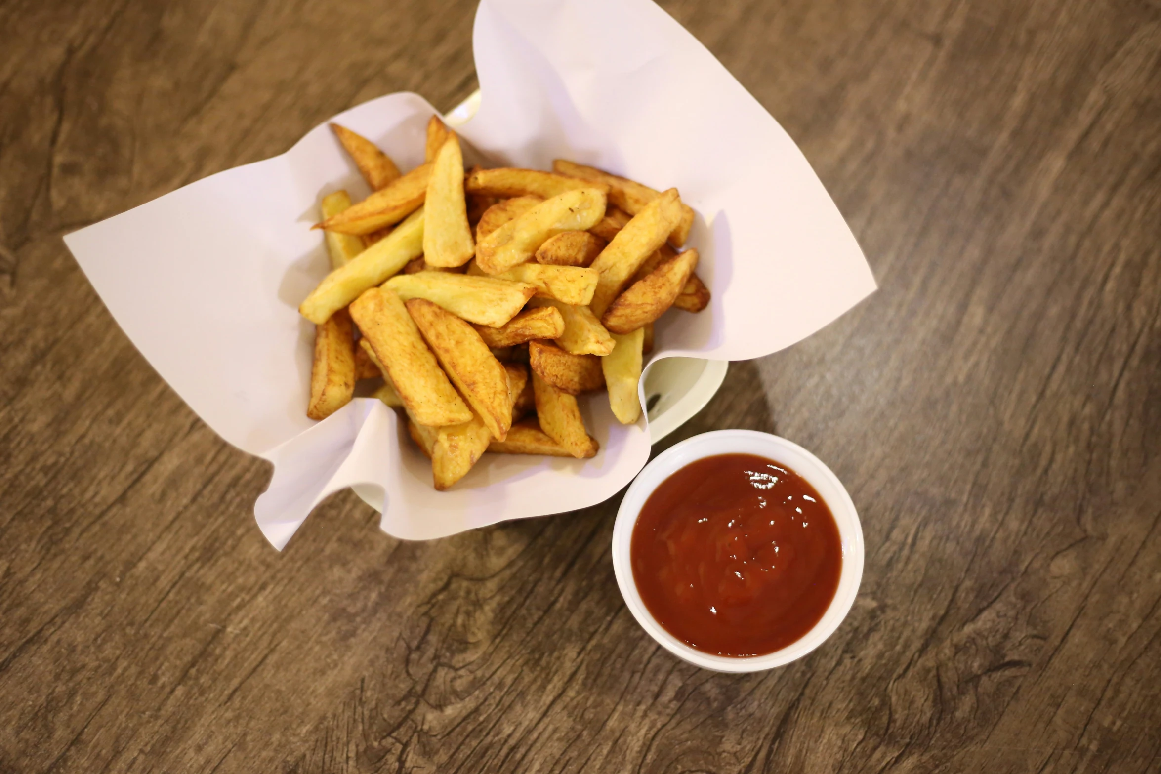 a pile of fries sitting next to a container with ketchup