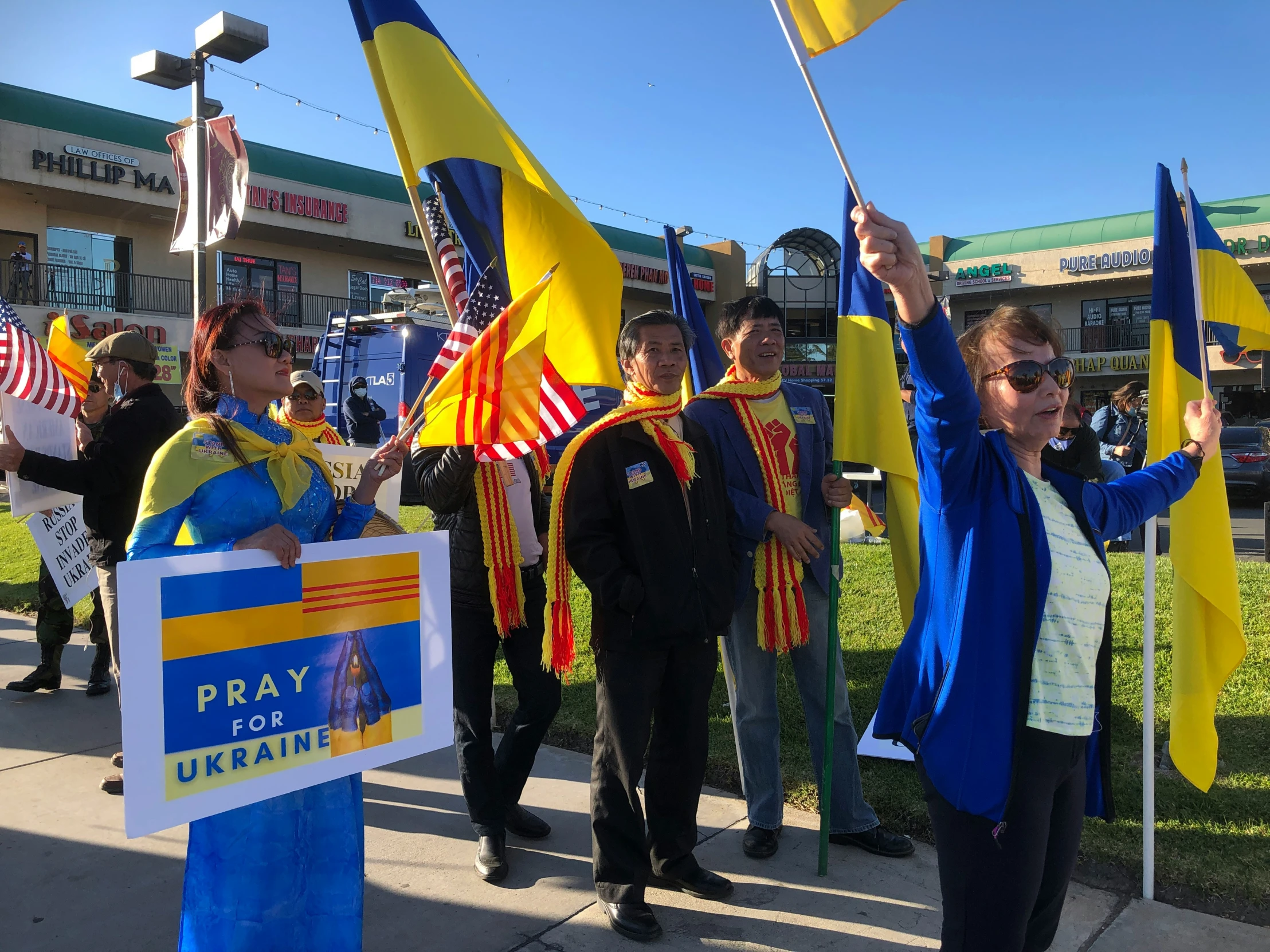 a group of people with flags and flags on the sidewalk