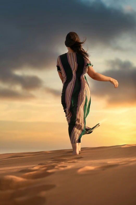 a woman in an ethnic dress walking across the sand