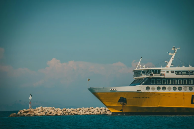 large yellow and white cruise ship near the rocky shore