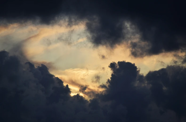 dark clouds in the sky with the sun breaking through them