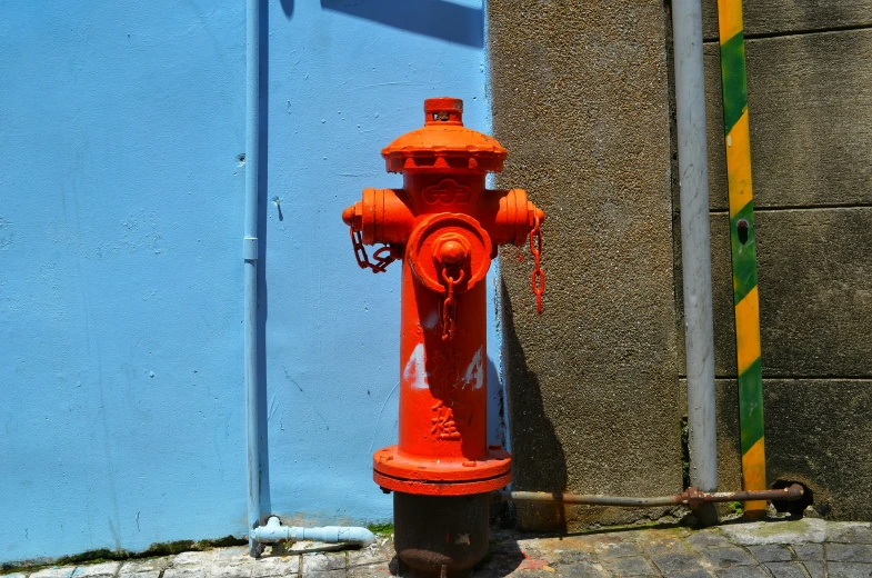 an orange fire hydrant sits in front of a blue building