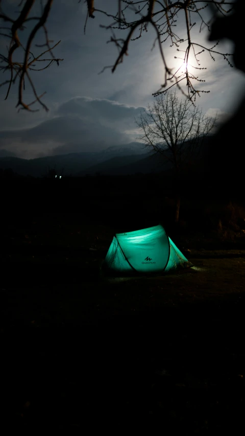 a glowing green tent sits in a darkened field