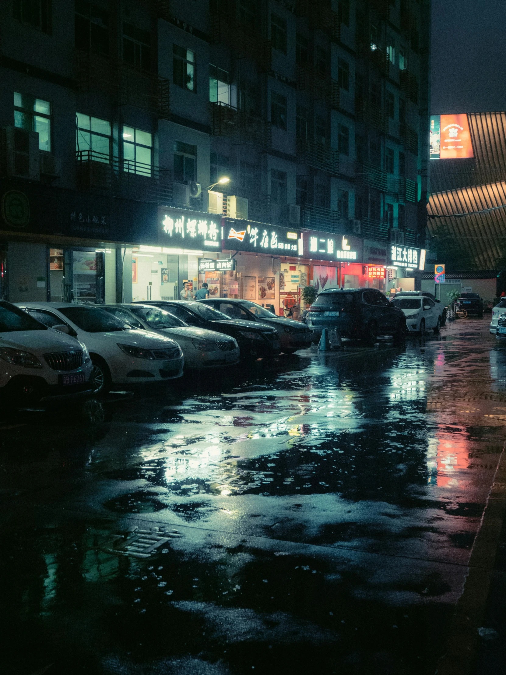 a very wet sidewalk at night with the street lights on