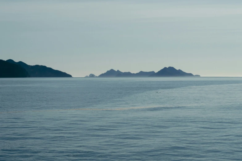 several mountain peaks near the ocean, with a boat in the water