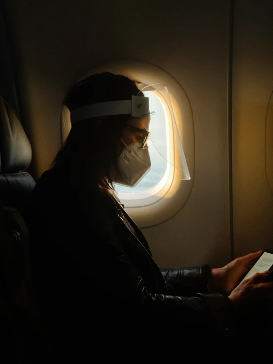 an older man uses his electronic device while sitting on an airplane