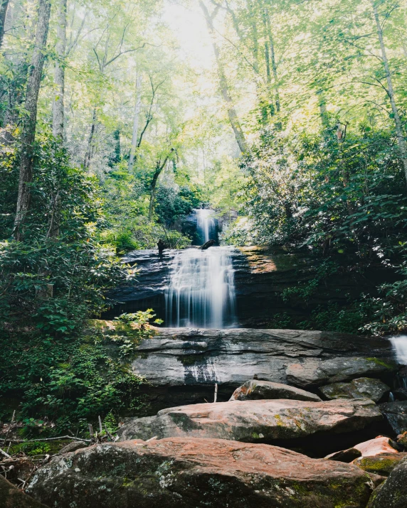 a waterfall surrounded by trees on the side of a cliff