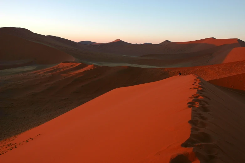 a large sand dune with mountains in the distance