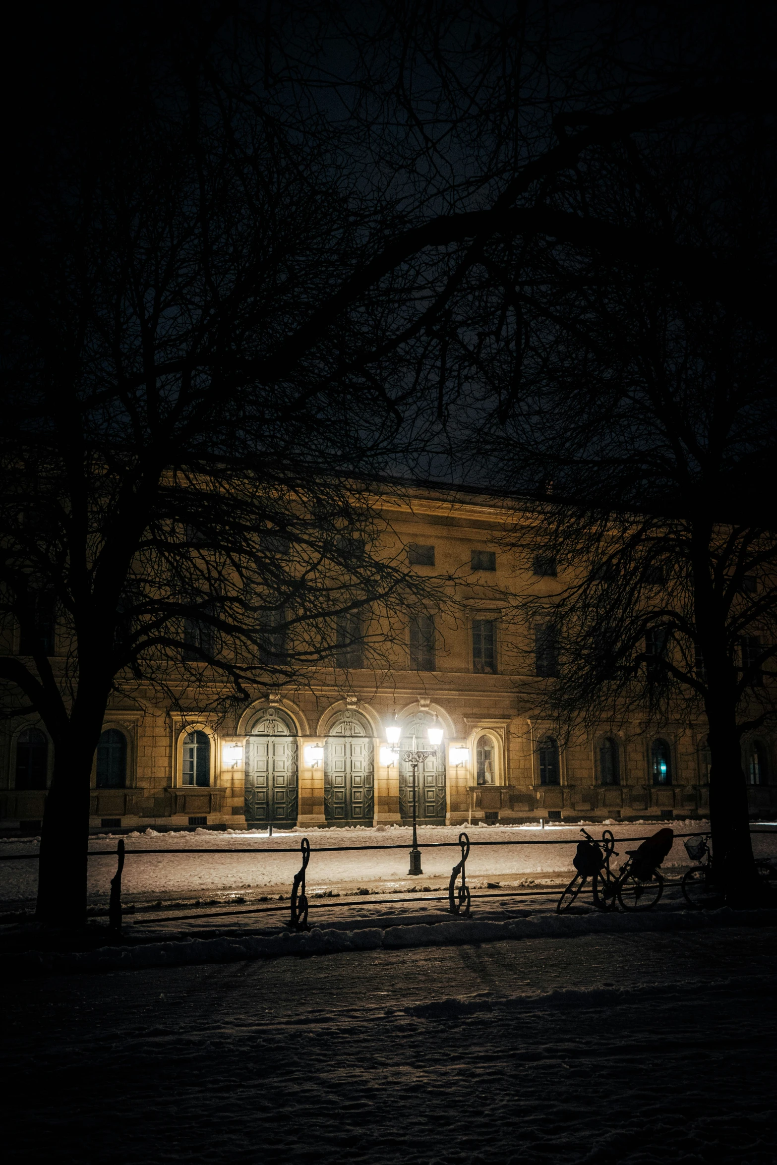 people walking in the snow outside of a building at night